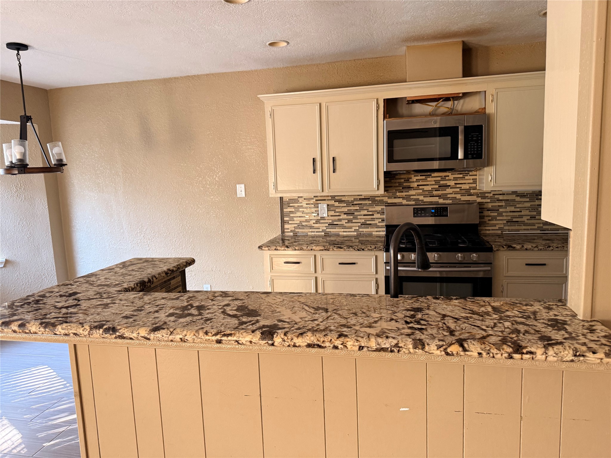 13726 Rampchester Lane Houston, TX 77015 - Photo 19 of 30 a kitchen with kitchen island granite countertop a stove top oven microwave and refrigerator