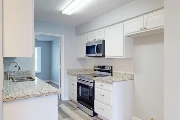 a kitchen with granite countertop cabinets stainless steel appliances and a sink