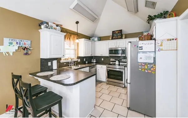 a kitchen with stainless steel appliances a refrigerator a sink a stove a table and chairs