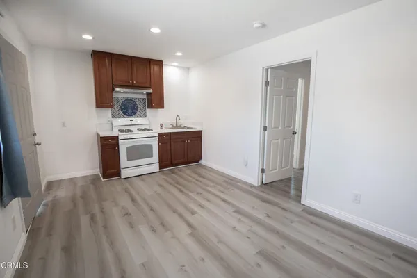 a view of kitchen with stainless steel appliances granite countertop a stove top oven a sink and dishwasher with wooden floor