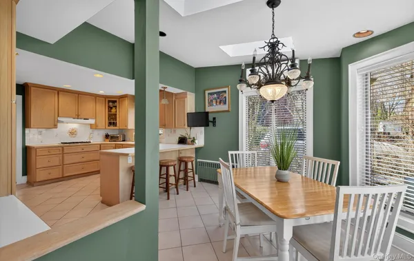 a open dining room with stainless steel appliances furniture a chandelier a large window and a kitchen view