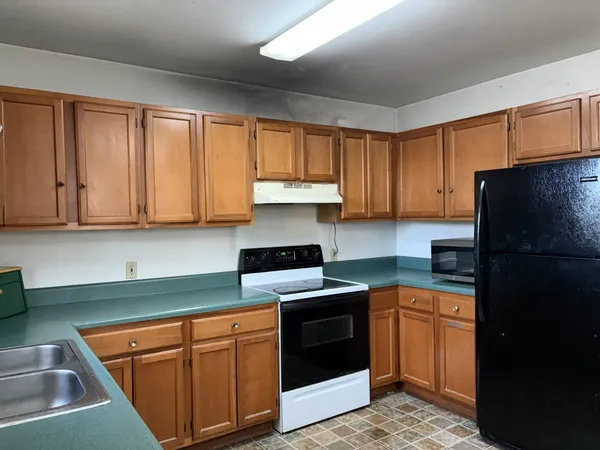 a kitchen with granite countertop a refrigerator stove top oven and sink