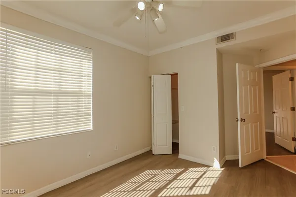 an empty room with windows and chandelier fan