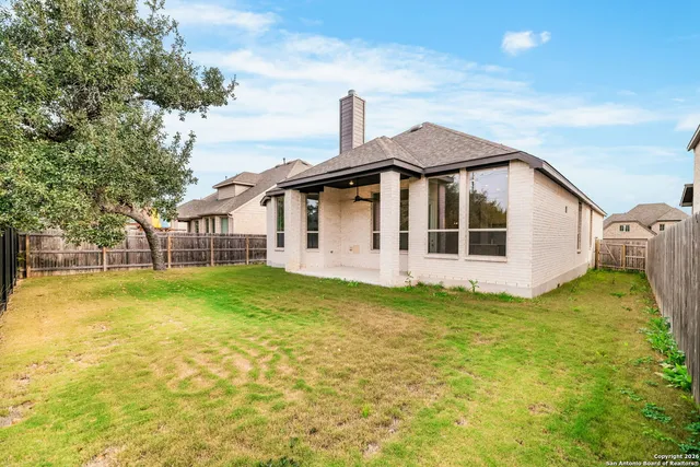 a white house that has a small yard and couches chairs with wooden fence