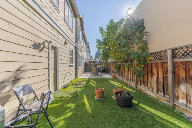 a view of a backyard with chairs potted plants and wooden fence