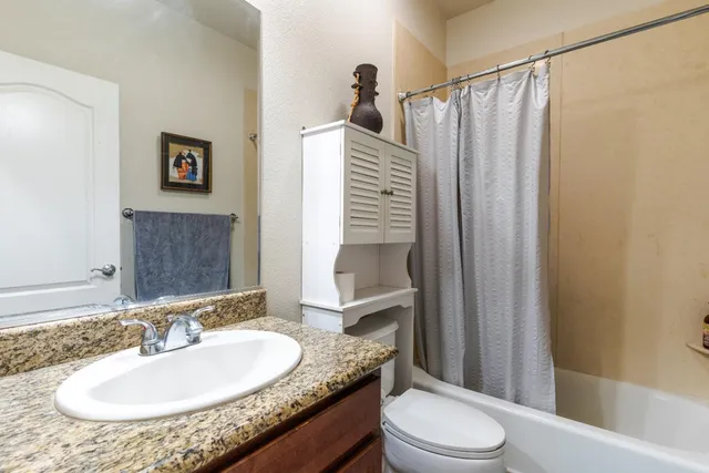 a bathroom with a granite countertop sink toilet and shower