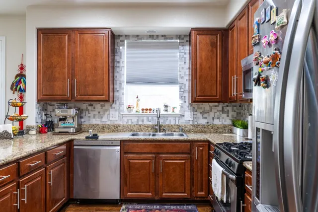 a kitchen with stainless steel appliances granite countertop a sink stove and refrigerator