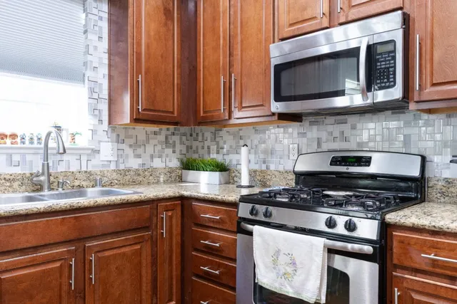 a kitchen with granite countertop a stove top oven microwave and cabinets
