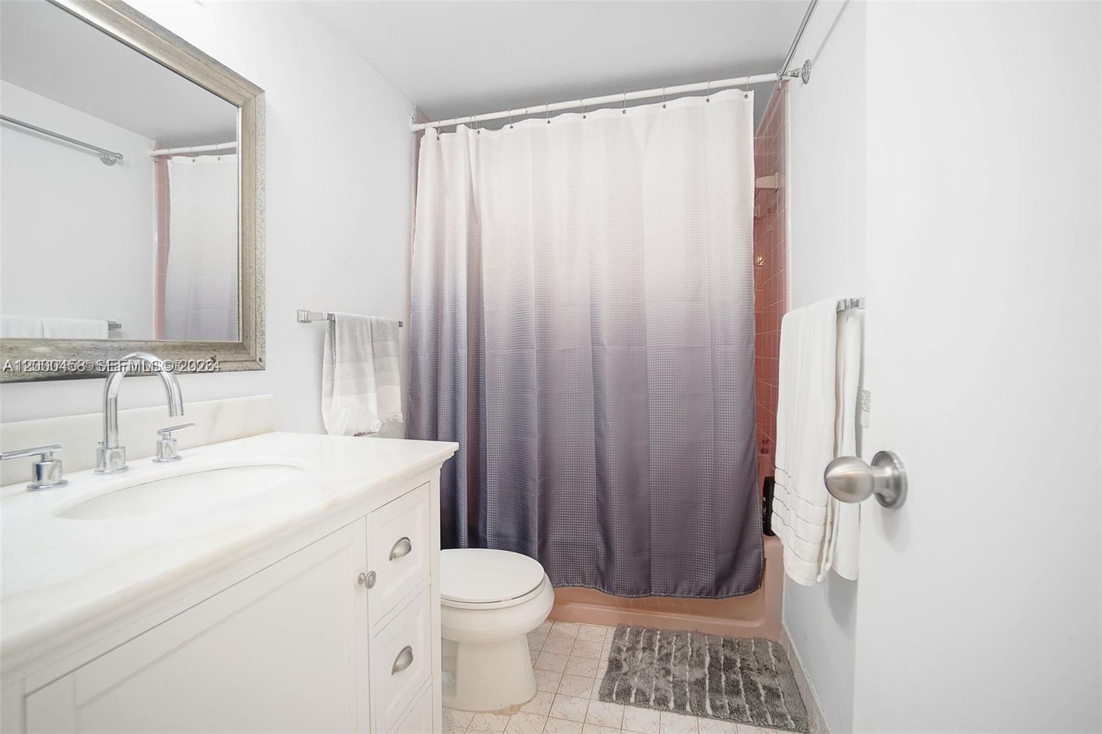 4747 Collins Avenue, Unit 1108 Miami Beach, FL 33140 - Photo 10 of 17 a bathroom with a sink a toilet a shower curtain and a large mirror