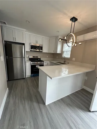 a kitchen with wooden floor white cabinets stainless steel appliances and wooden floor