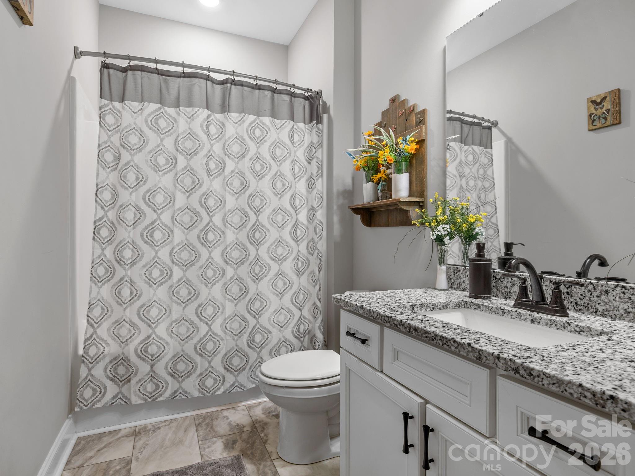 1076 McSwain Road Chesnee, SC 29323 - Photo 21 of 36 a bathroom with a granite countertop sink a toilet and a shower curtain