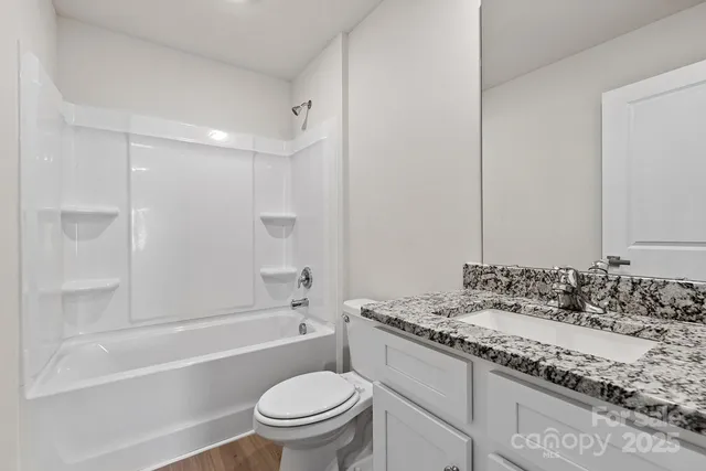 a bathroom with a granite countertop sink a toilet and bathtub