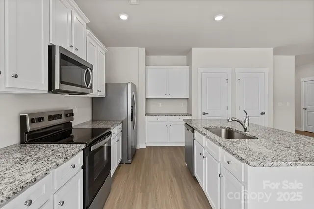 a kitchen with granite countertop a sink dishwasher stove and oven with wooden cabinets