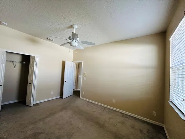 an empty room with a window and a ceiling fan