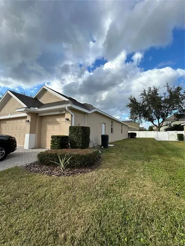 a view of a house with a yard and large tree