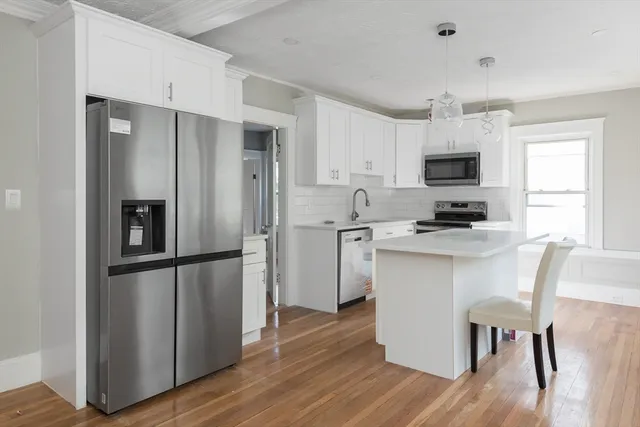 a kitchen with white cabinets stainless steel appliances and wooden floor