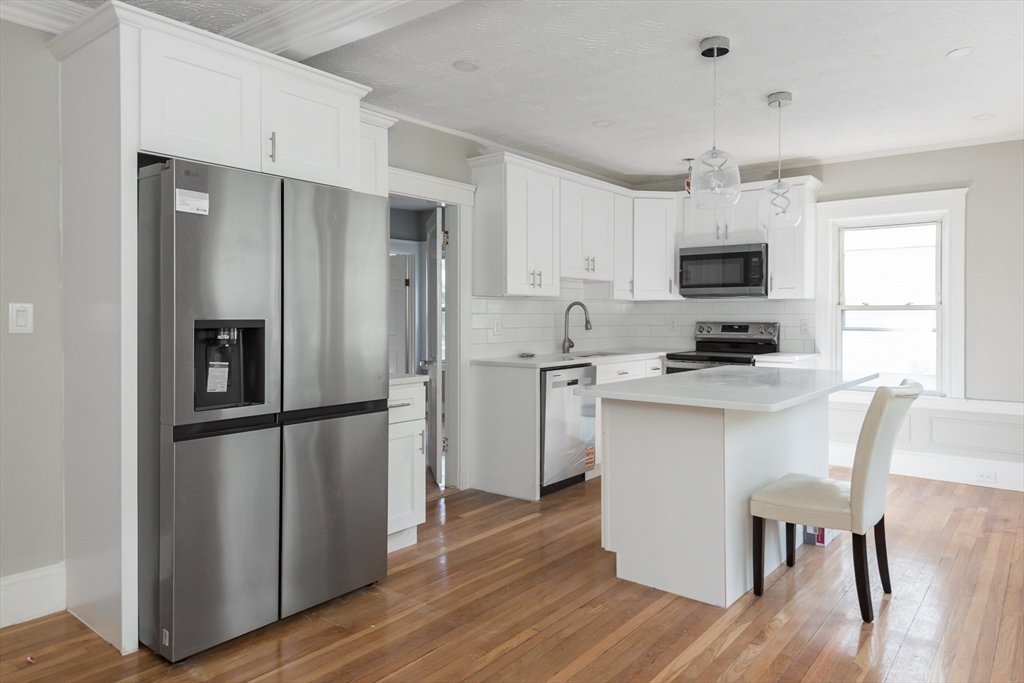 112 Brush Hill Road Milton, MA 02186 - Photo 2 of 42 a kitchen with white cabinets stainless steel appliances and wooden floor