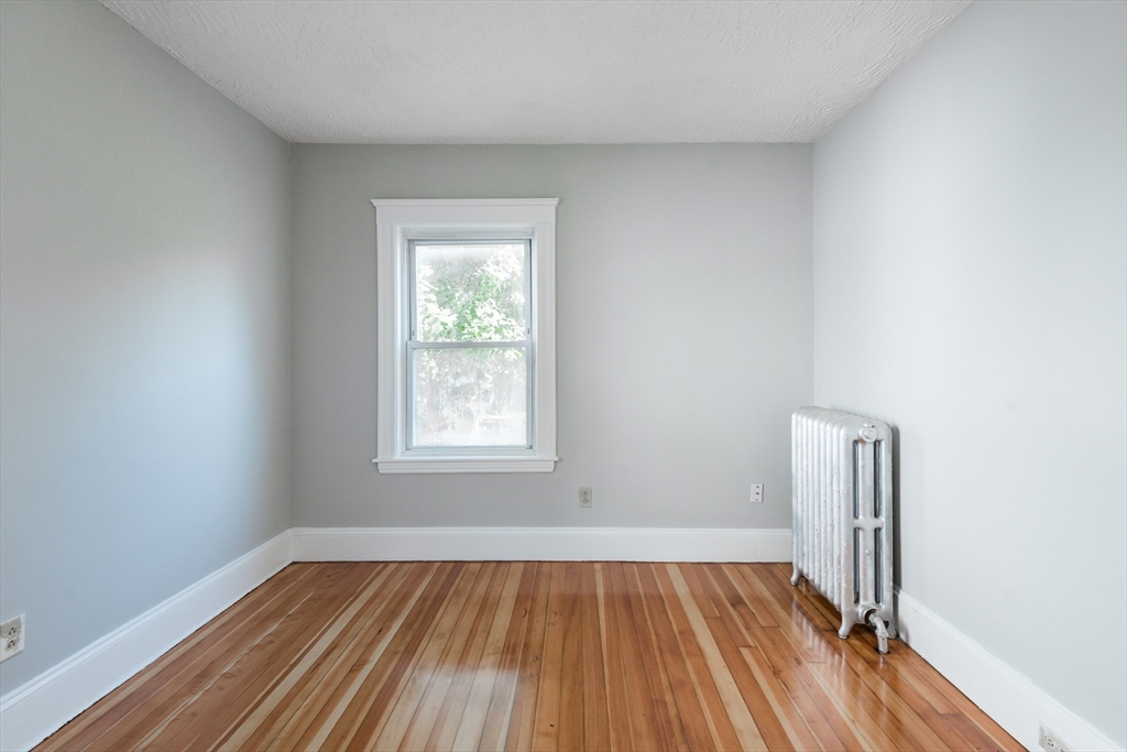 112 Brush Hill Road Milton, MA 02186 - Photo 23 of 42 an empty room with a window and wooden floor
