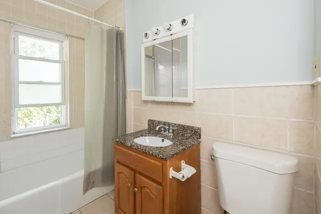 a bathroom with a granite countertop sink a toilet and shower