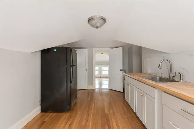 a kitchen with sink a refrigerator and wooden floor