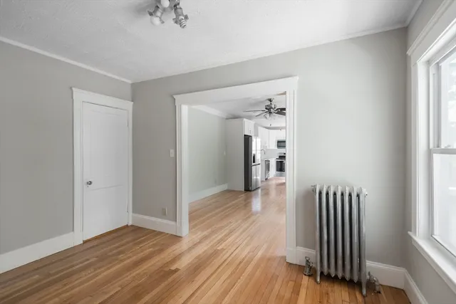 a view of a hallway with wooden floor and a bathroom