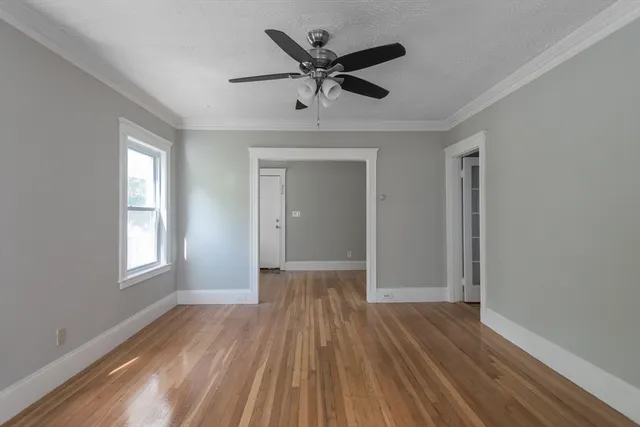 a view of empty room with wooden floor and ceiling fan