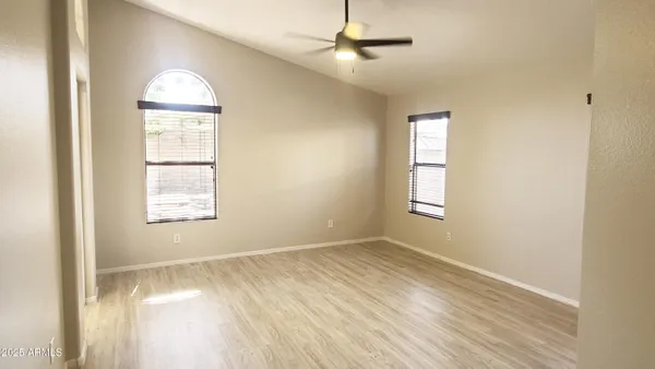 a view of empty room with wooden floor and fan