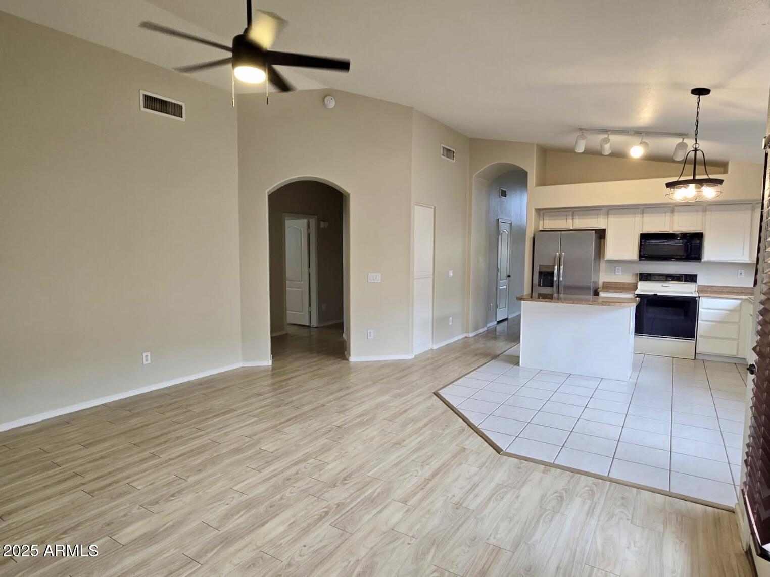 1729 East Pony Lane Gilbert, AZ 85295 - Photo 5 of 31 an empty room with wooden floor a ceiling fan a kitchen view and a fireplace
