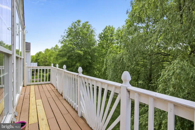 a balcony with wooden floor and trees in the background