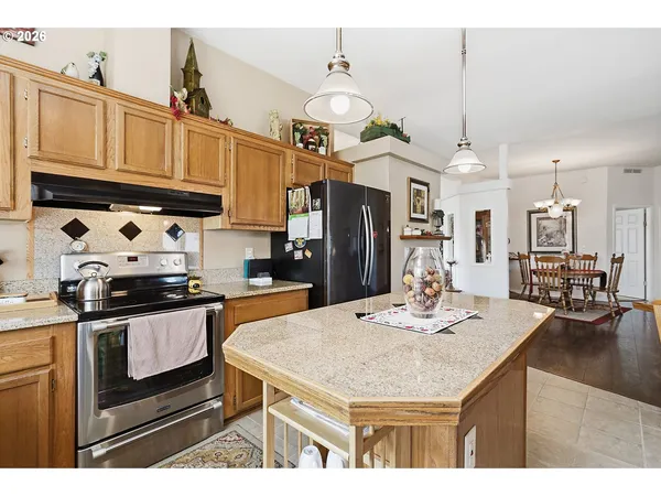 a kitchen with stainless steel appliances kitchen island granite countertop a sink a stove and refrigerator