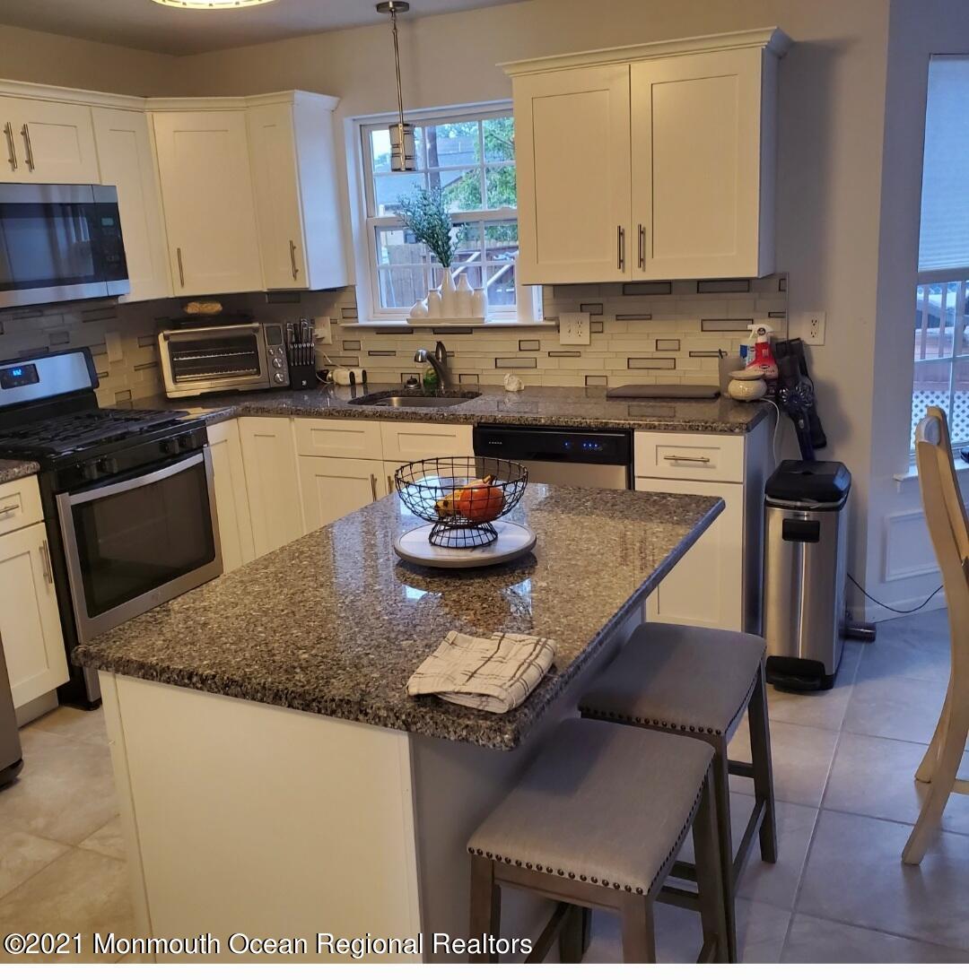 128 Captain Road Manahawkin, NJ 08050 - Photo 4 of 20 a kitchen with stainless steel appliances granite countertop a sink a stove and a wooden cabinets