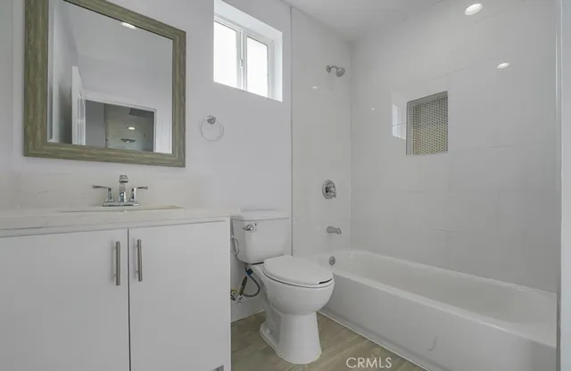 a bathroom with a toilet sink vanity tub and mirror