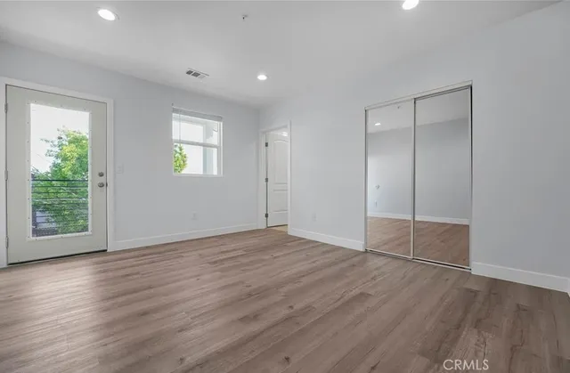 an empty room with wooden floor and windows
