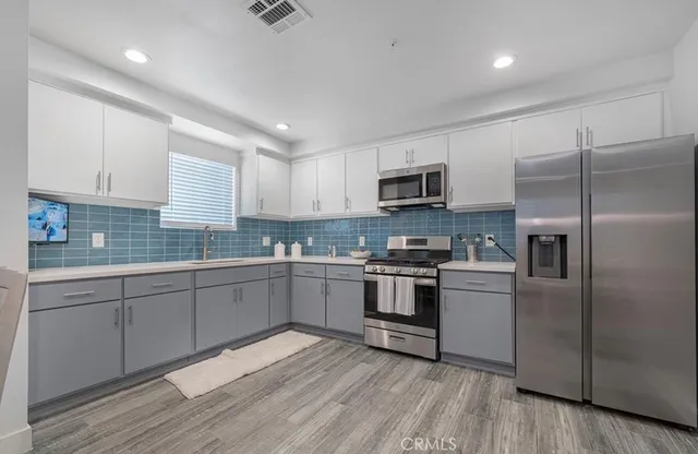a kitchen with cabinets stainless steel appliances and a window