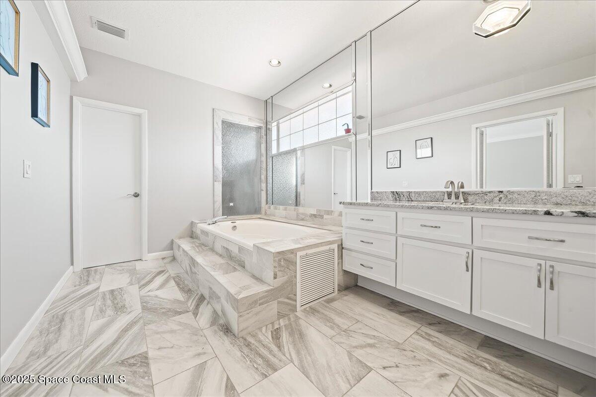 505 Sanderling Drive Indialantic, FL 32903 - Photo 34 of 63 a spacious bathroom with a granite countertop sink a mirror and a bathtub