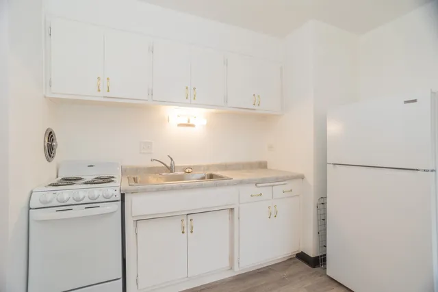 a kitchen with stainless steel appliances granite countertop white refrigerator stove and white cabinets