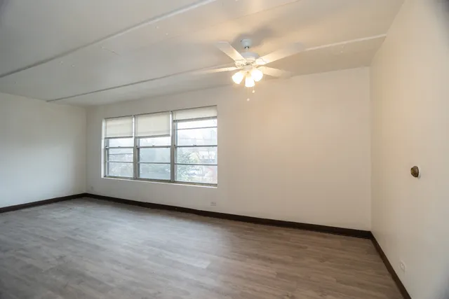 an empty room with a window and a fan