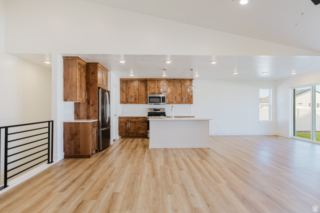433 North 600 West Smithfield, UT 84335 - Photo 11 of 40 Open-concept living space featuring wood-finish flooring, a kitchen island, stainless steel appliances, and wood cabinetry