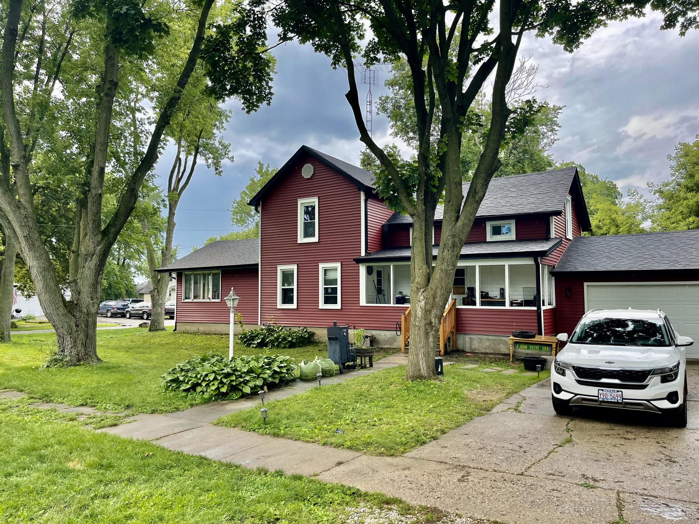 211 State Street Maple Park, IL 60151 - Photo 2 of 19 a car parked in front of a brick house with a large tree