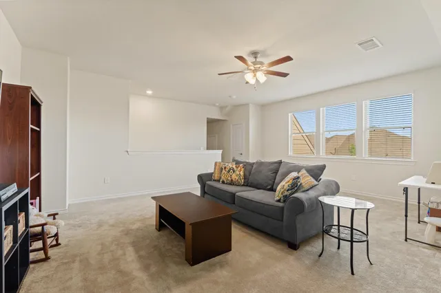 a living room with furniture a ceiling fan and a window
