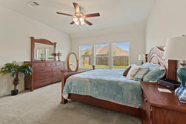 a bedroom with a bed a large window and potted plants on the dresser