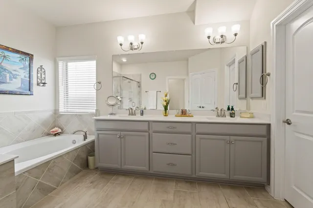 a spacious bathroom with a double vanity sink mirror and bathtub