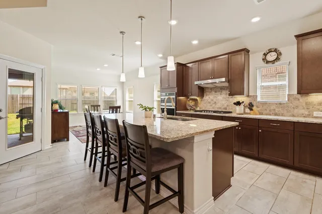 a kitchen with a dining table chairs and sink