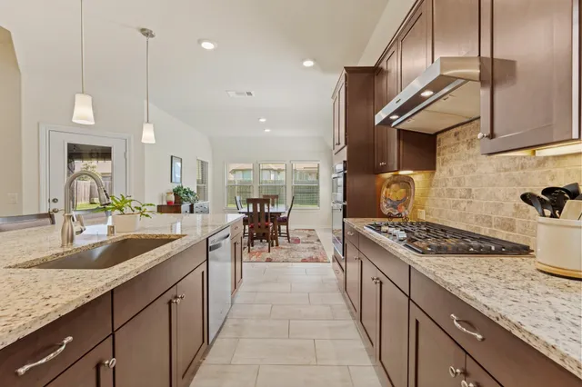 a kitchen with stainless steel appliances granite countertop a sink a stove and a wooden floors