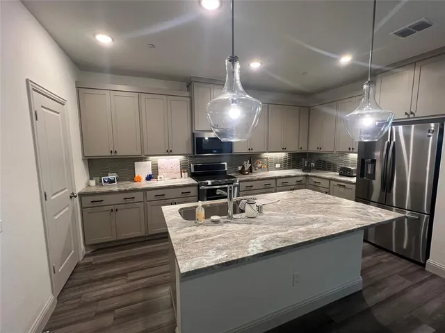 a kitchen with stainless steel appliances granite countertop a sink refrigerator and cabinets