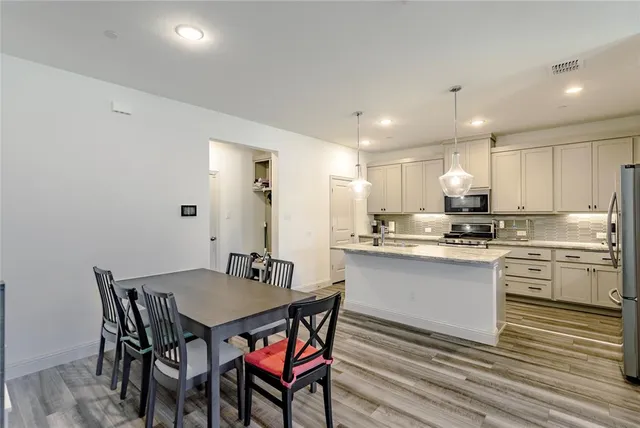 a kitchen with stainless steel appliances granite countertop a dining table chairs and sink