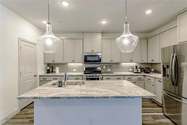 a kitchen with kitchen island granite countertop a sink stainless steel appliances and white cabinets