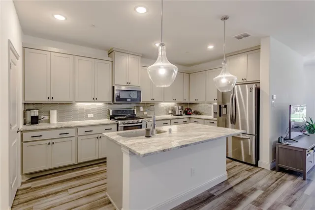 a kitchen with kitchen island a sink stainless steel appliances and cabinets