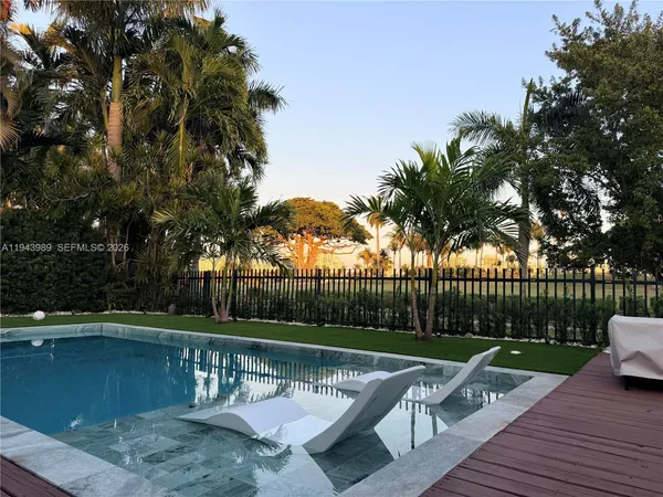 a view of swimming pool with seating area and trees in the background