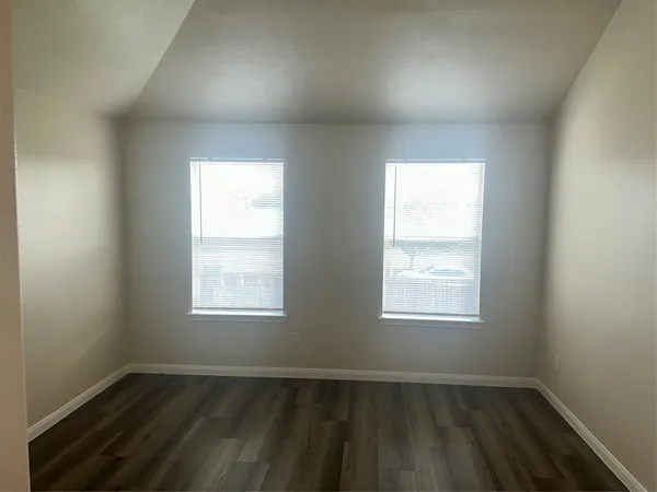 an empty room with wooden closet and windows